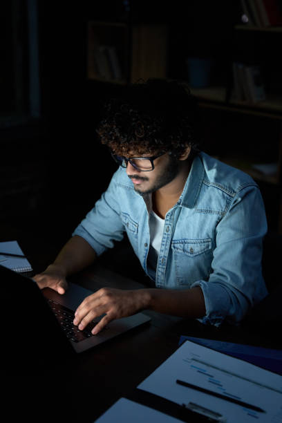 istock Young indian business man student working online at night using laptop. 1384673024