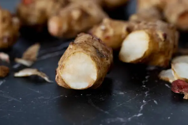 Cut Jerusalem artichoke on a dark granite table. A closeup.