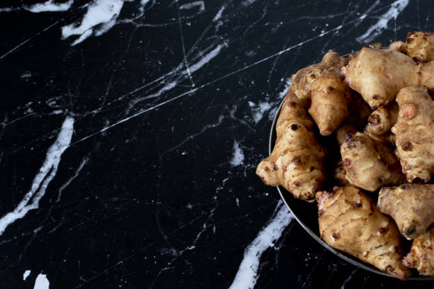 istock Jerusalem artichoke root vegetable in a bowl isolated on a dark granite table 1384673223