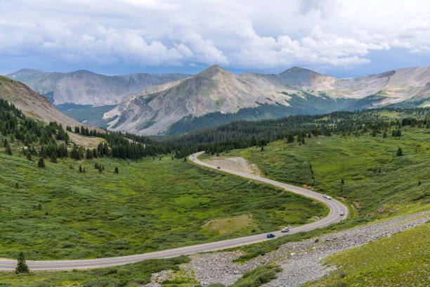 cottonwood pass - ein panoramablick auf eine bergstraße im sommer, die sich in einem grünen tal östlich des gipfels des cottonwood pass windet. - continental divide stock-fotos und bilder