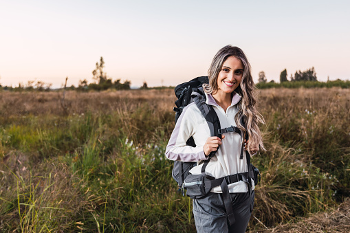 Young woman with a backpack on, in the middle of the field. Digital nomad. Copy space