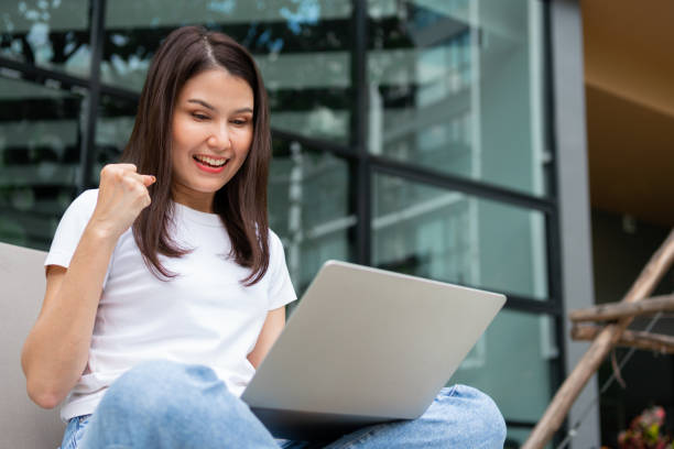 istock Happy young entrepreneur woman sitting on tanning bed beside pool and using laptop computer for remote online working digital, online business project in quiet yard of resort house, Work on vacation 1384696900