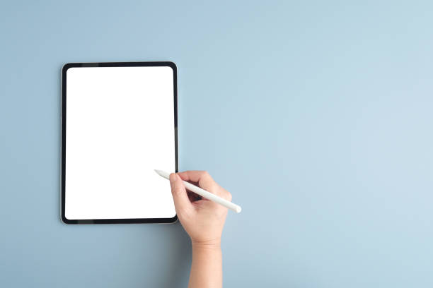 istock Hand holding pen over  digital tablet with blank on screen isolated on gray background, banner for template, mock up, topview, flat lay, communication technology 1384699758