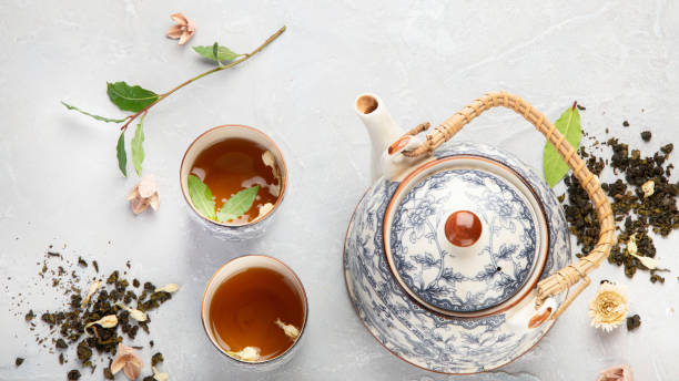 istock Asian teapot with herbal tea on light background. 1384701516