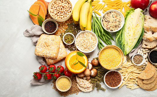 Selection of good carbohydrates sources - vegetables, fruits, grains, legumes, nuts and seeds on white background, top view.