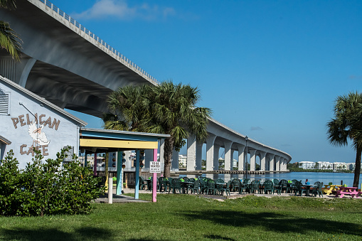 Outdoor cafe at Flagler Park with view of Roosevelt Bridge in the background on a clear sunny day along the St. Lucie River in downtown Stuart, FL. Pelican cafe is now Hudson's on the River in 2022