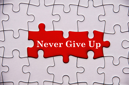 Never give up text on red background with missing jigsaw puzzle. Motivational concept