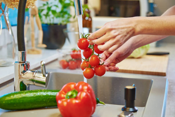 istock Woman washing tomato at kitchen sink 1384726625