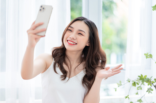 Young Asian woman using smartphone at home in the morning