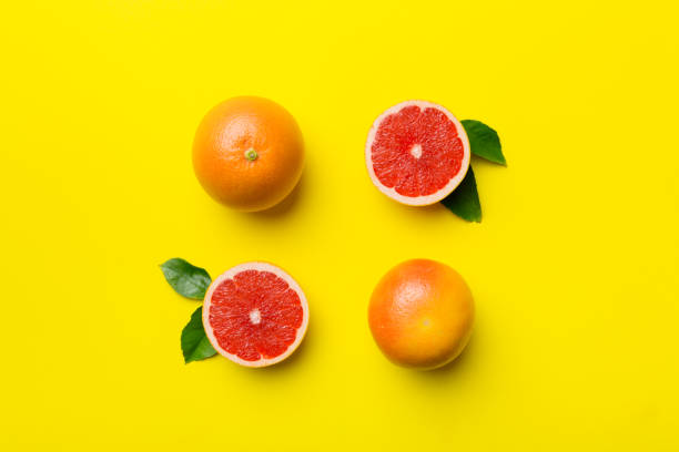 istock fresh Fruit grapefruit with Juicy grapefruit slices on colored background. Top view. Copy Space. creative summer concept. Half of citrus in minimal flat lay with copy space 1384747942