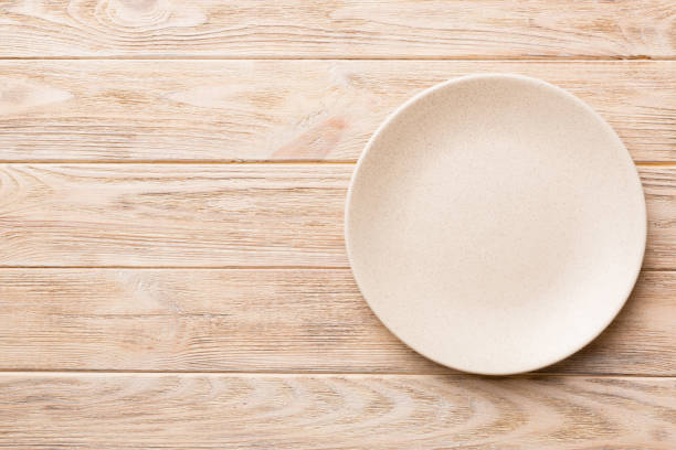 istock Top view of empty light plate on wooden background. Empty space for your design 1384747979