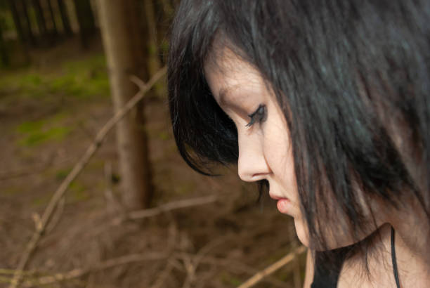 Punk emo girl, young adult with black hair and eyeliner, close-up Punk emo girl, young adult with black hair and eyeliner, looking down, forest, close-up, horizontal black hair emo girl stock pictures, royalty-free photos & images