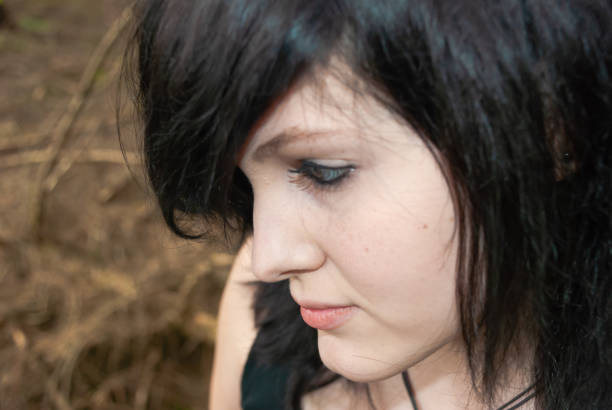 Punk emo girl, young adult with black hair and eyeliner, close-up Punk emo girl, young adult with black hair and eyeliner, looking away, forest, close-up, horizontal black hair emo girl stock pictures, royalty-free photos & images
