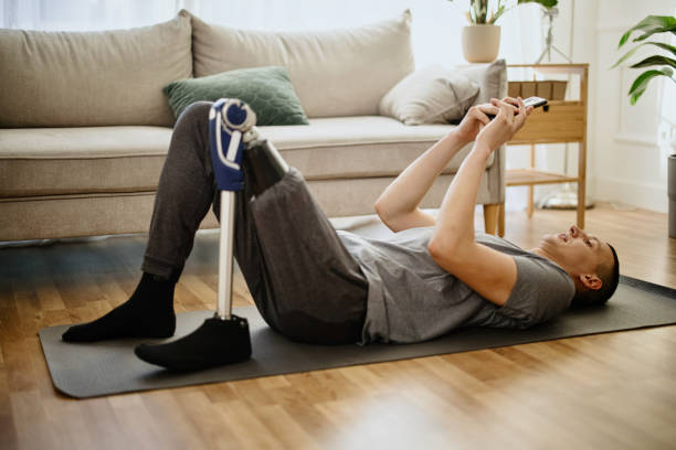 istock Male amputee with prosthesis taking break from exercises using smartphone 1384751478