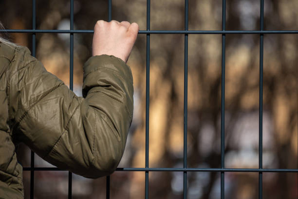 istock Child refugee behind a metal fence 1384756940