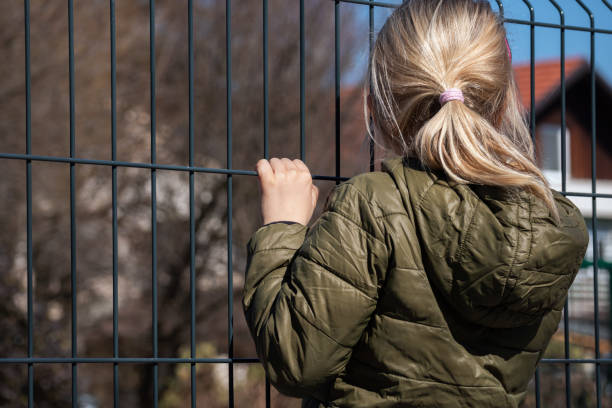 istock Child refugee behind a metal fence 1384756941
