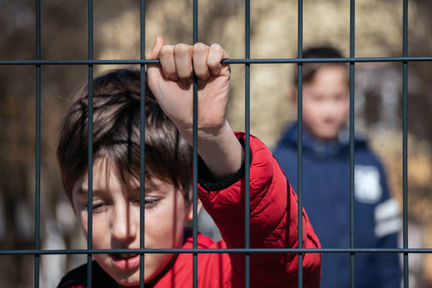 istock Child refugee behind a metal fence 1384756962