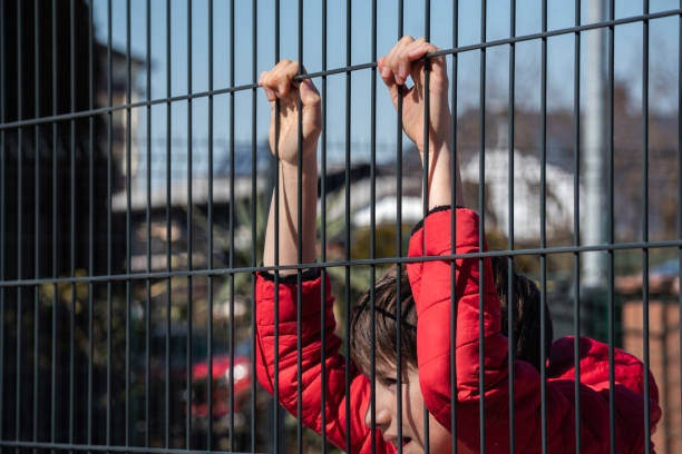 istock Child refugee behind a metal fence 1384756965