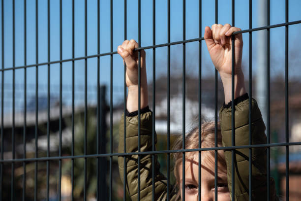 istock Child refugee behind a metal fence 1384756966