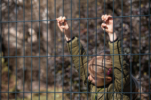 istock Child refugee behind a metal fence 1384756968