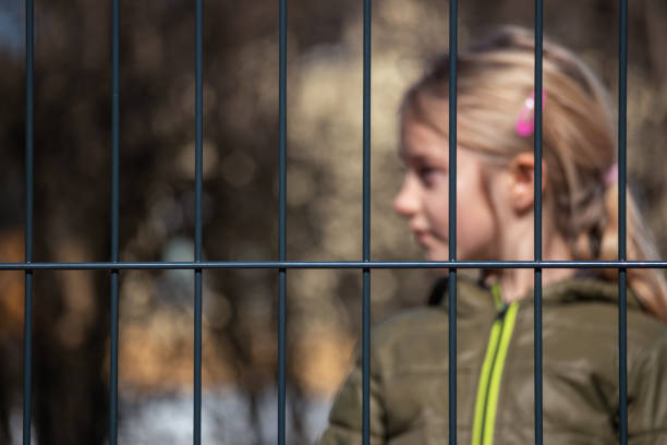 istock Child refugee behind a metal fence 1384756974
