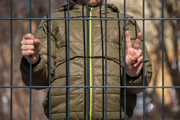 istock Child refugee behind a metal fence 1384757004