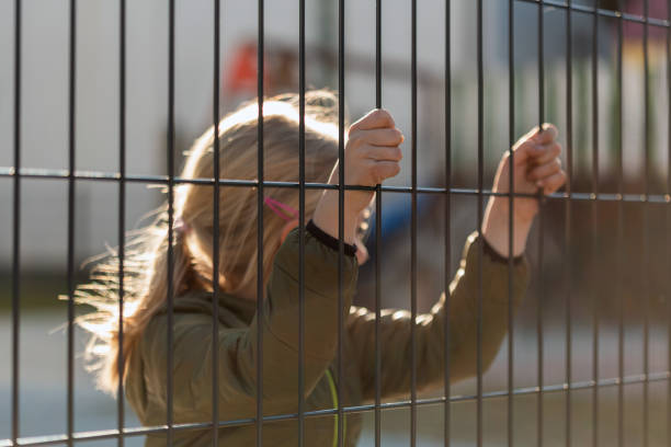 istock Child refugee behind a metal fence 1384757054