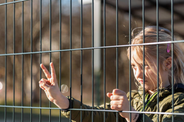 istock Child refugee behind a metal fence 1384757055