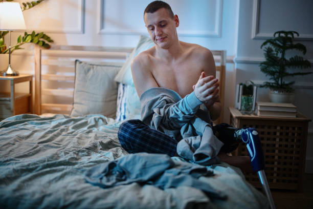 Disabled young man with prosthetic leg, changing clothes and getting ready for sleep