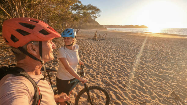 istock Mountain biking couple relax on beach, at sunrise 1384769512