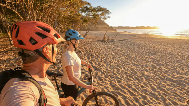 istock Mountain biking couple relax on beach, at sunrise 1384769517