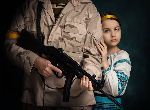 une fille d’ukraine se cache derrière son père. l’homme est prêt à la protéger de l’ennemi - military armed forces patriotism flag photos et images de collection