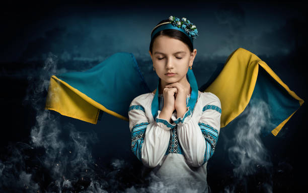 A girl from Ukraine is praying for her country. The girl has wings that are created from the flag of Ukraine A girl from Ukraine is praying for her country. The girl has wings that are created from the flag of Ukraine. There is a war going on. ukrainian language stock pictures, royalty-free photos & images