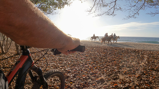 He heads towards group on horseback, by the Pacific Ocean
