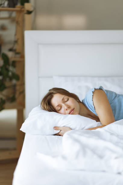 портрет молодой женщины, наслаждающейся сном в постели, крупным планом, приподнятым видом, обнимающей подушкой - лежать на боку стоковые фото и изображения