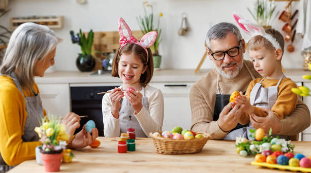 istock Happy little children creating beautiful painted eggs for Easter with loving senior grandparents 1384786049