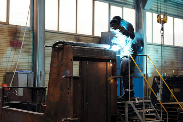 istock Contemporary worker or welder in protective mask and uniform repairing machine 1384786210