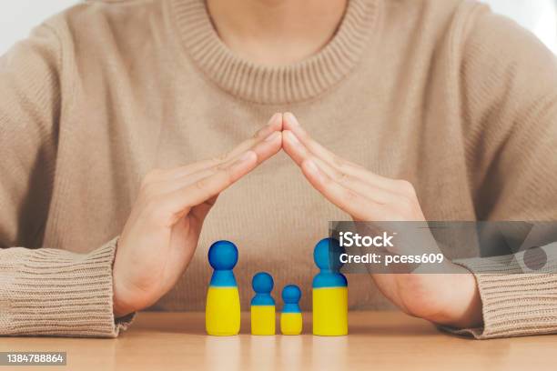 Love Ukraine Concept Woman Hands Protecting Family In The Shape Of A House With Mother Father And Children Painted In Colors Of Ukrainian Flag In The Home Provide Housing To Immigrants Stock Photo - Download Image Now
