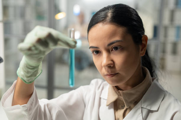 istock Contemporary scientist looking at flask with blue liquid substance 1384798387