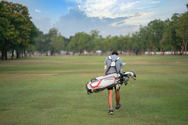 boy golfer walking with his golf bag on the fairway