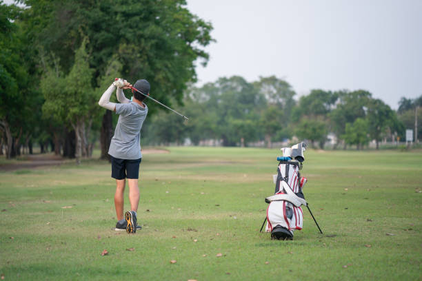 istock Young man playing golf on a golf course in the sun, Golfers hit sweeping golf course in the summer 1384802843