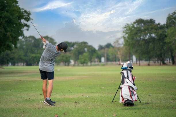istock Young man playing golf on a golf course in the sun, Golfers hit sweeping golf course in the summer 1384802845