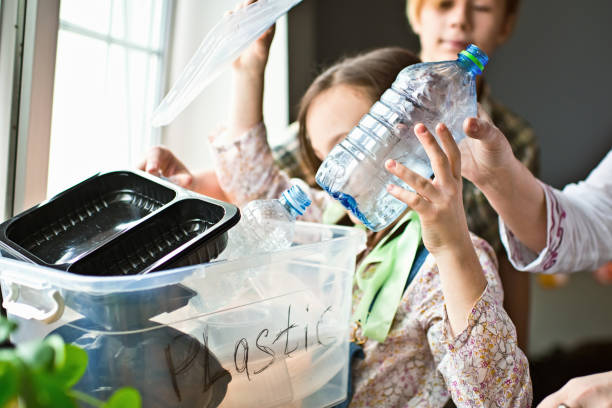Family  sorting out waste for recycling Mother teaching her children how to  separate plastic, glass and paper waste at home climate action photos stock pictures, royalty-free photos & images