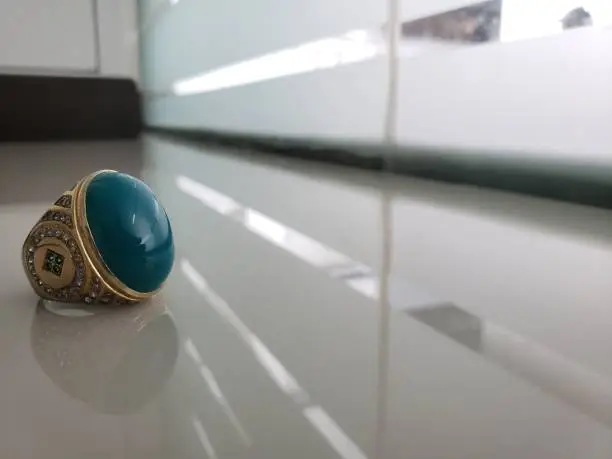 Photo of Chrysocolla in Chalcedony agate or gem silica ring or original Bacan stone from Bacan Island, Indonesia in a very beautiful blue color on gray ceramic with ornament background