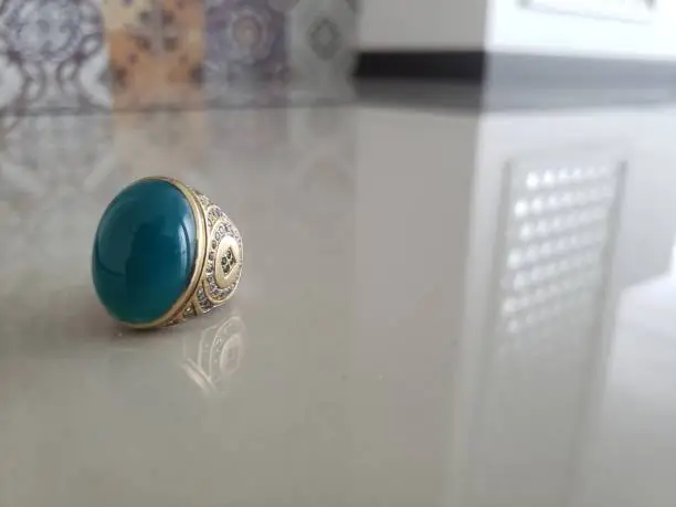 Photo of Chrysocolla in Chalcedony agate or gem silica ring or original Bacan stone from Bacan Island, Indonesia in a very beautiful blue color on gray ceramic with ornament background