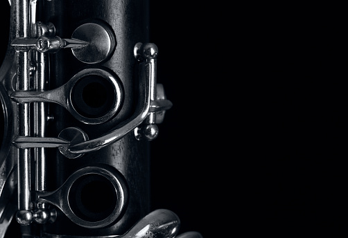 part of the old clarinet body, with the silver mechanisms on the wood. Black background and free space for text