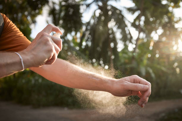 homem aplicando repelente de insetos em sua mão - insect repellant mosquito bug bite spraying - fotografias e filmes do acervo