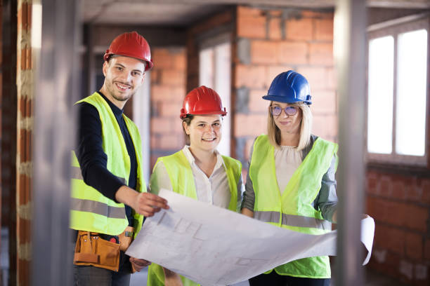 istock team of engineers in vests and hard hats with schematics on a construction site 1384820796