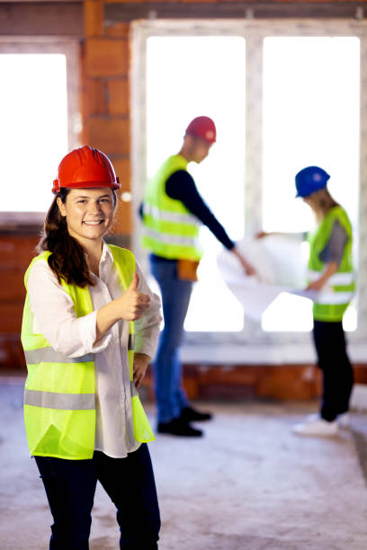 istock construction site engineer showing thumbs up. her team of engineers working in the background 1384820910