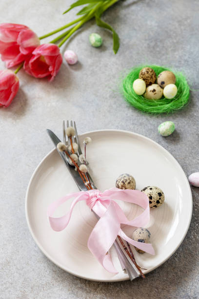 istock Festive Easter table setting with painted eggs, spring flowers and cutlery on light grey tabletop. Table setting for Happy Easter day. 1384825517